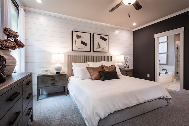 carpeted bedroom with ceiling fan, ensuite bath, wood walls, and crown molding