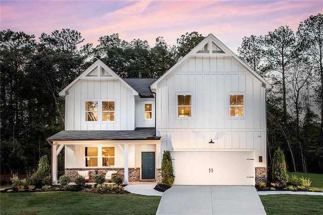 modern farmhouse featuring a yard, covered porch, and a garage