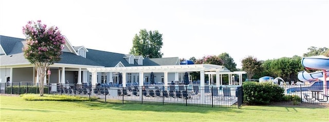 rear view of house with a pergola, a lawn, and a playground