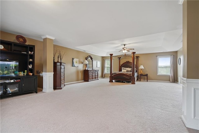 carpeted bedroom featuring ceiling fan, a raised ceiling, and ornate columns