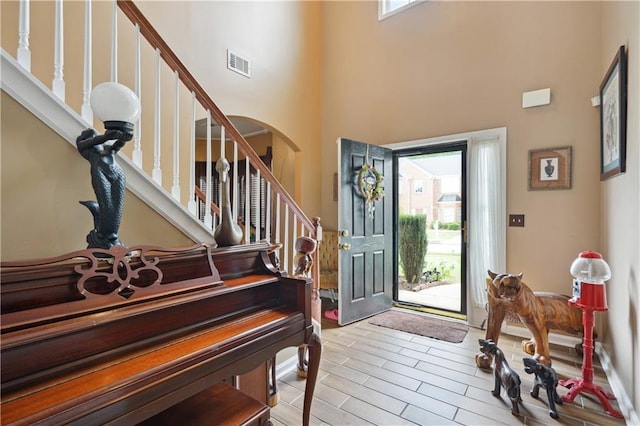 foyer entrance featuring a towering ceiling, light hardwood / wood-style floors, and a wealth of natural light