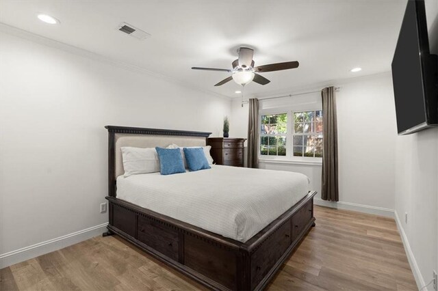 bedroom featuring ceiling fan, crown molding, and light hardwood / wood-style floors