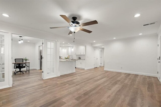 unfurnished living room with ceiling fan, light hardwood / wood-style flooring, and ornamental molding