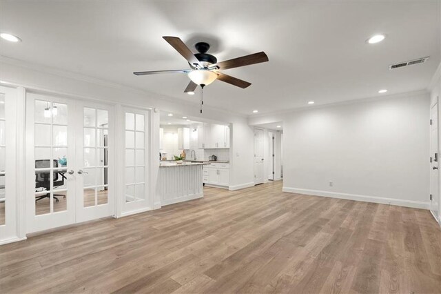 unfurnished living room with ceiling fan, light wood-type flooring, french doors, and ornamental molding