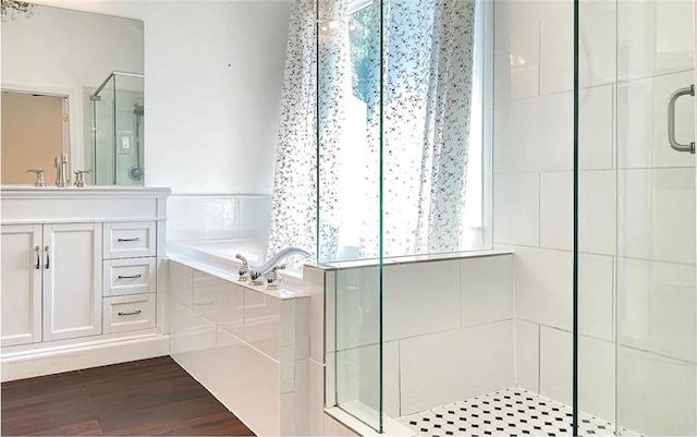 full bathroom with a stall shower, a garden tub, vanity, and wood finished floors