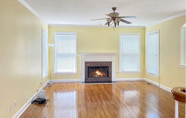 unfurnished living room featuring a brick fireplace, baseboards, ornamental molding, and hardwood / wood-style floors