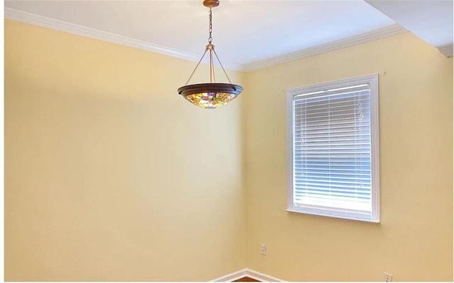 empty room featuring baseboards and crown molding