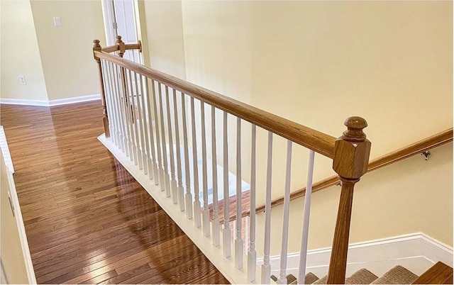 stairway with wood finished floors and baseboards