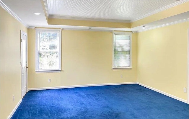 spare room featuring ornamental molding, dark colored carpet, a healthy amount of sunlight, and baseboards