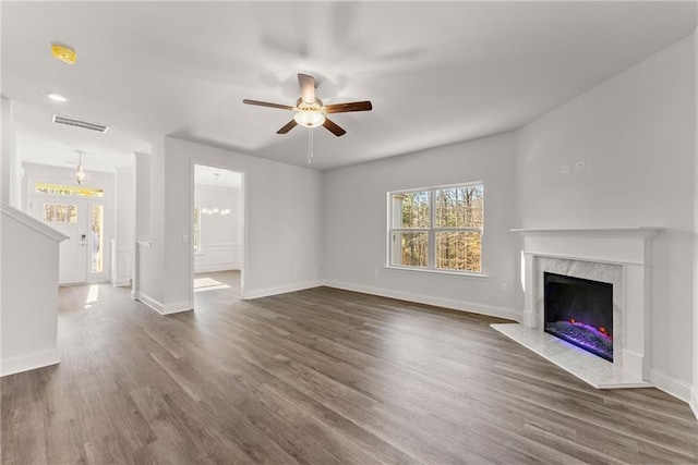 unfurnished living room with a ceiling fan, a premium fireplace, baseboards, visible vents, and dark wood-type flooring