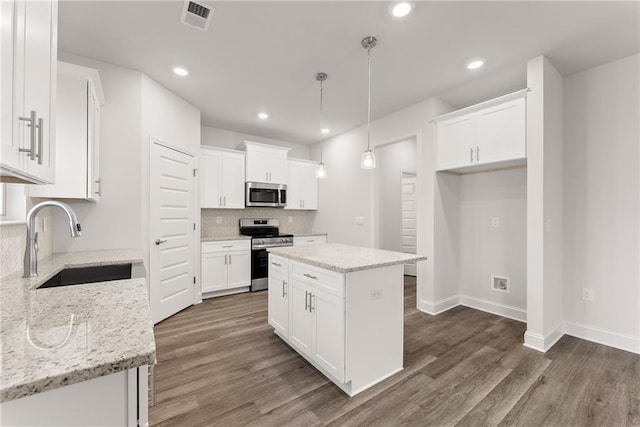 kitchen featuring a sink, stainless steel appliances, visible vents, backsplash, and dark wood-style floors