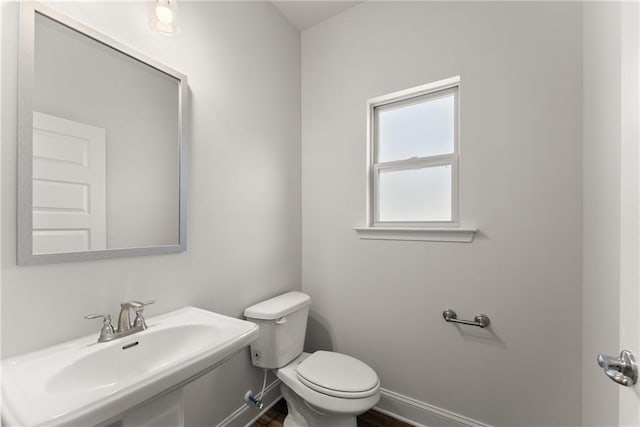 bathroom featuring a sink, toilet, baseboards, and wood finished floors