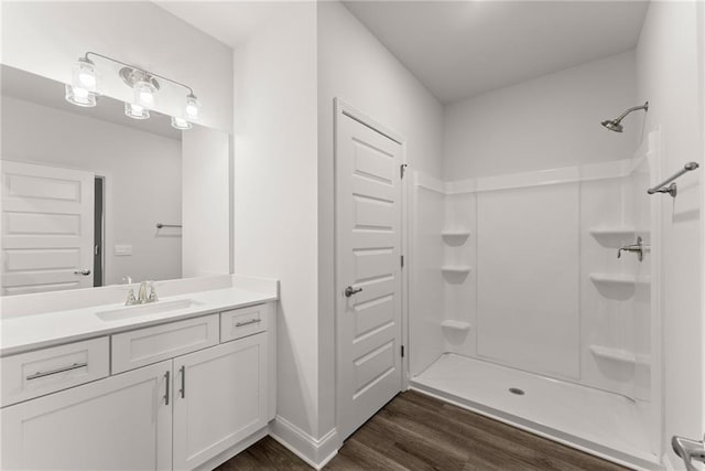 full bath with a shower, baseboards, vanity, and wood finished floors