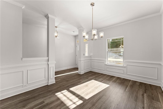 unfurnished dining area featuring crown molding, a decorative wall, wainscoting, a chandelier, and dark wood-style floors
