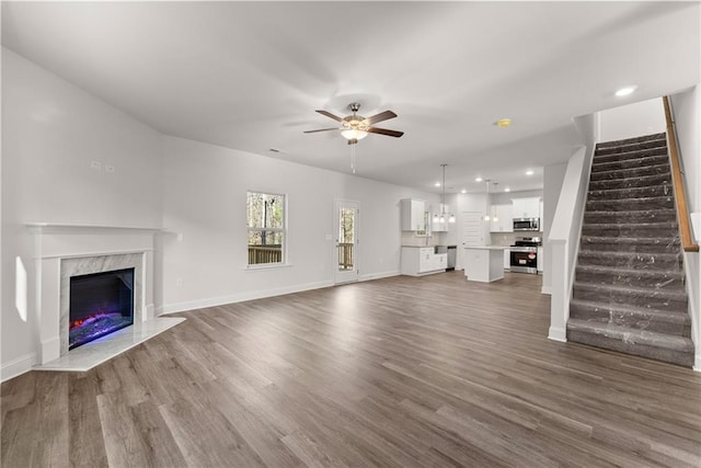 unfurnished living room featuring recessed lighting, dark wood-type flooring, a ceiling fan, and stairs