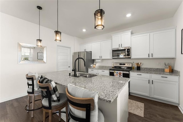 kitchen featuring dark wood-style floors, appliances with stainless steel finishes, a kitchen island with sink, white cabinetry, and a sink