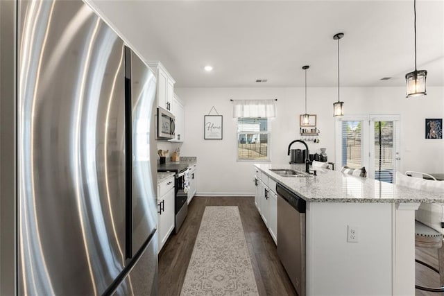 kitchen featuring dark wood finished floors, a breakfast bar area, appliances with stainless steel finishes, white cabinets, and a sink