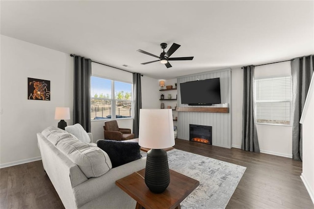 living room with ceiling fan, a fireplace, baseboards, and wood finished floors