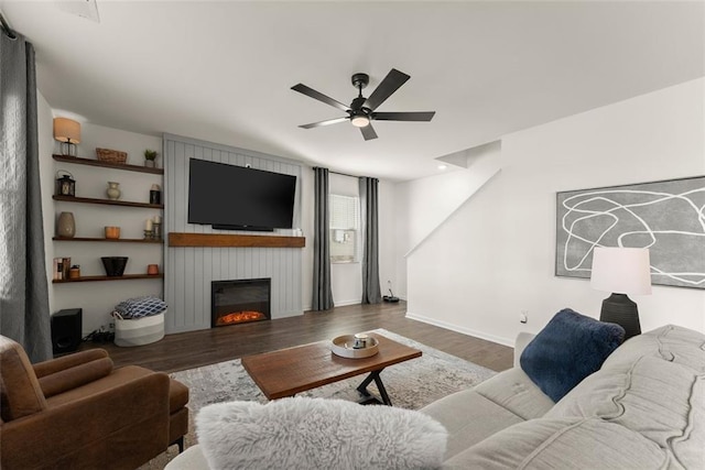 living room featuring a large fireplace, baseboards, a ceiling fan, and wood finished floors