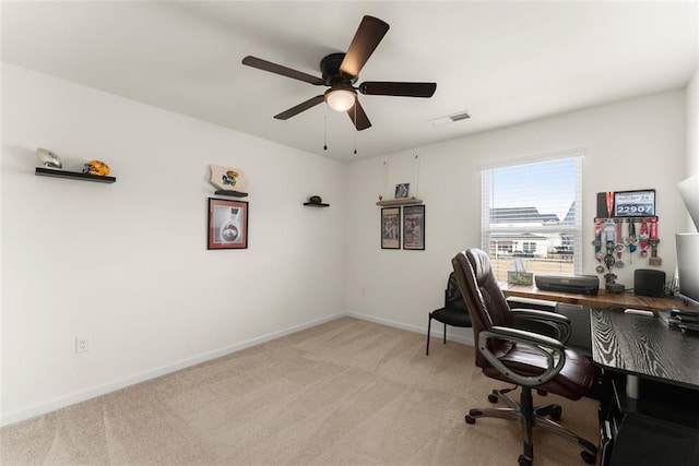 office space featuring baseboards, a ceiling fan, visible vents, and light colored carpet