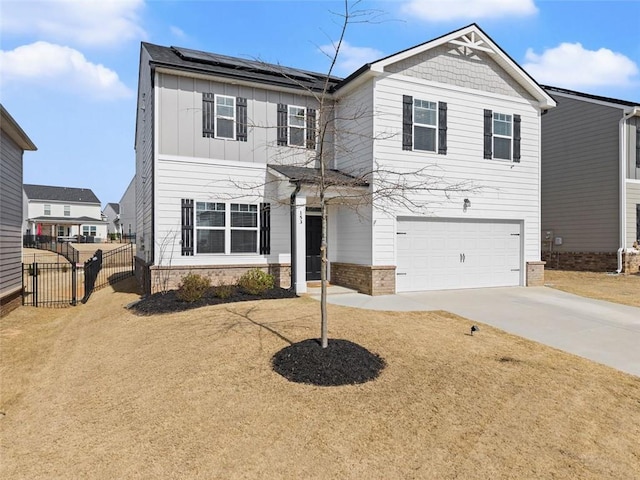 traditional home with board and batten siding, roof mounted solar panels, fence, a garage, and driveway