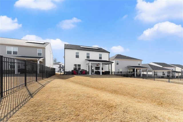 rear view of house with a yard, a fenced backyard, and roof mounted solar panels