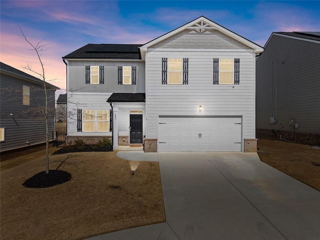 traditional-style home featuring board and batten siding, driveway, a garage, and solar panels