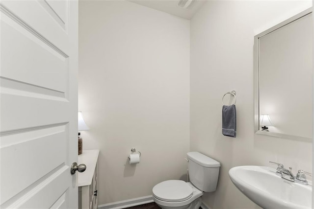 bathroom with toilet, baseboards, and a sink