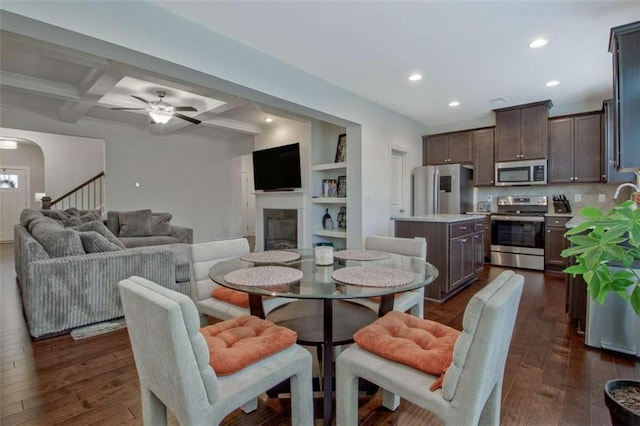 dining space featuring coffered ceiling, ceiling fan, built in features, beam ceiling, and dark hardwood / wood-style flooring