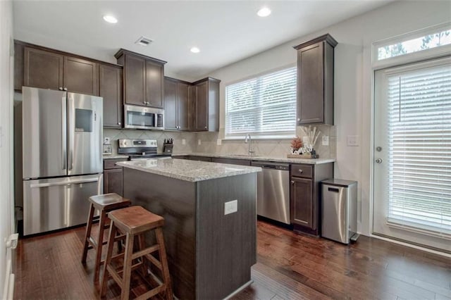 kitchen with a center island, backsplash, dark wood-type flooring, sink, and appliances with stainless steel finishes