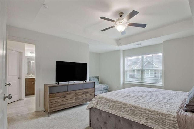 carpeted bedroom featuring ceiling fan, a raised ceiling, and ensuite bathroom