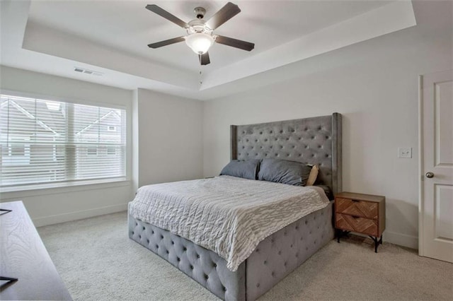 bedroom featuring light carpet, a raised ceiling, and ceiling fan