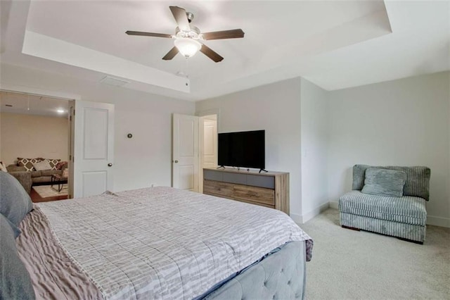 carpeted bedroom with a tray ceiling and ceiling fan