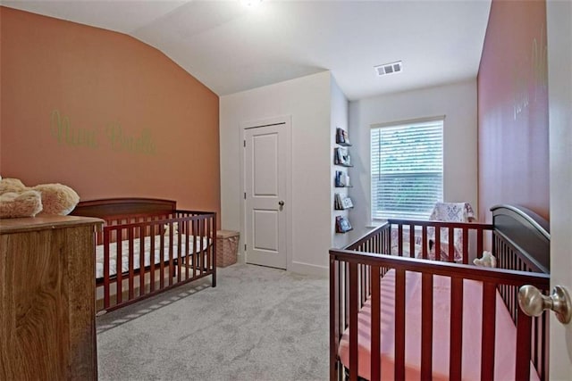 bedroom featuring a crib, light colored carpet, and vaulted ceiling