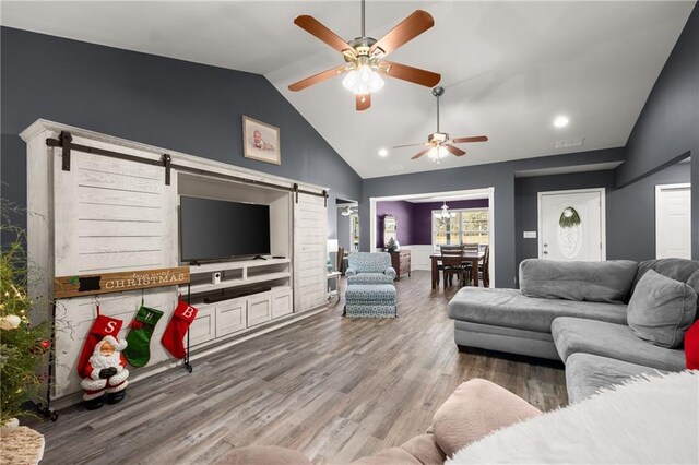 living room featuring lofted ceiling, ceiling fan, hardwood / wood-style flooring, and a barn door