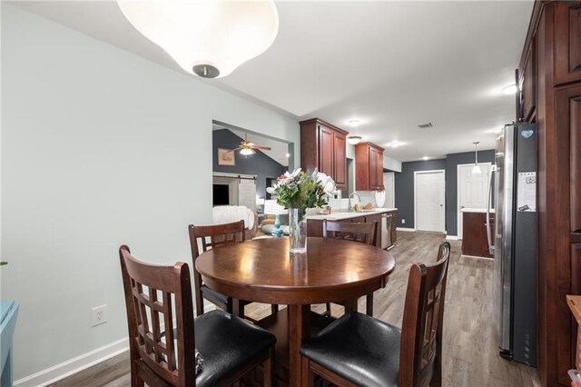 dining area featuring sink, ceiling fan, and dark wood-type flooring