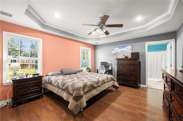 bedroom featuring light wood-type flooring, a raised ceiling, and ceiling fan