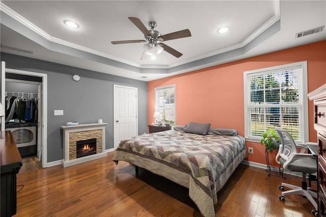 bedroom with a raised ceiling, ceiling fan, crown molding, and dark hardwood / wood-style floors