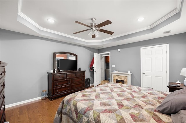 bedroom with ceiling fan, light hardwood / wood-style floors, ornamental molding, and a raised ceiling