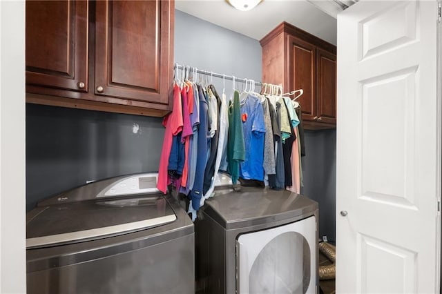 clothes washing area featuring washer and dryer and cabinets