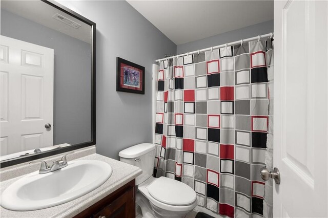 bathroom with toilet, vanity, and curtained shower