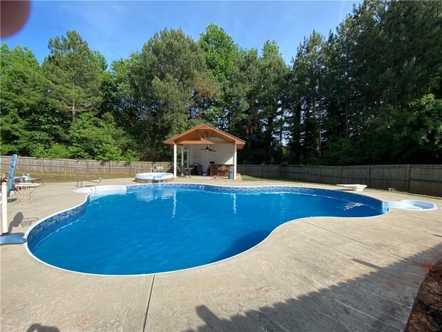 view of swimming pool featuring ceiling fan, a jacuzzi, a diving board, and a patio area