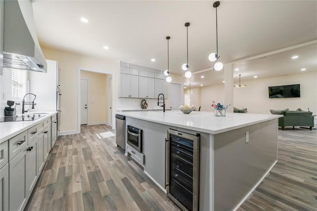 kitchen featuring hanging light fixtures, hardwood / wood-style floors, a spacious island, wine cooler, and oven