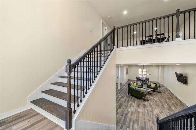 staircase with a high ceiling and wood-type flooring