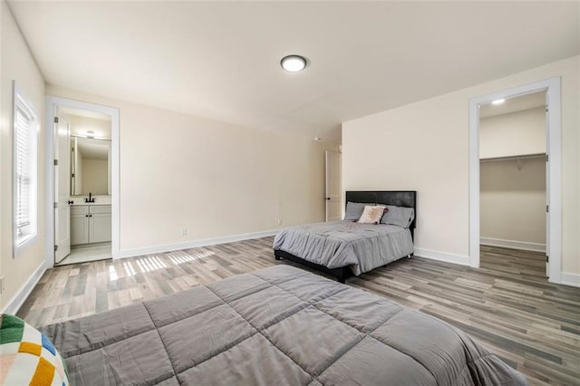 unfurnished bedroom with a walk in closet, connected bathroom, and light wood-type flooring