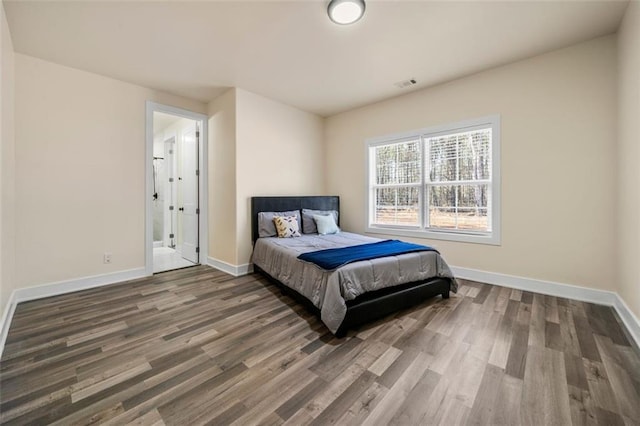 bedroom featuring dark wood-type flooring and ensuite bath