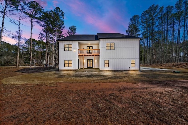 back house at dusk featuring a balcony