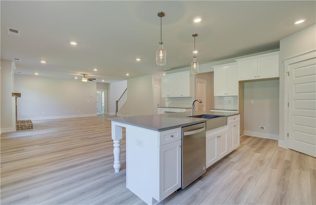 kitchen with ceiling fan, white cabinetry, dishwasher, and an island with sink