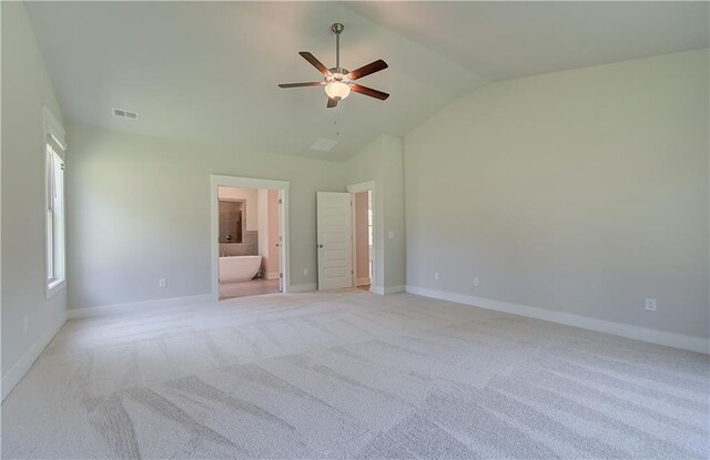 unfurnished bedroom featuring ceiling fan, light colored carpet, vaulted ceiling, and ensuite bathroom