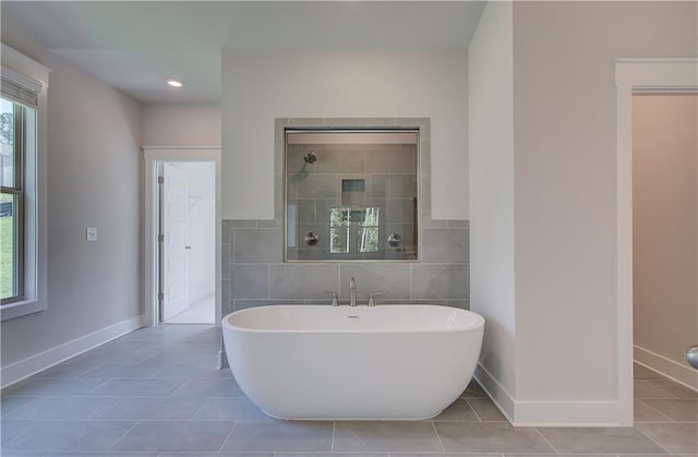 bathroom with tile walls, tile patterned floors, and a bath